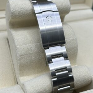 Green dial watch on wrist with stainless steel bracelet